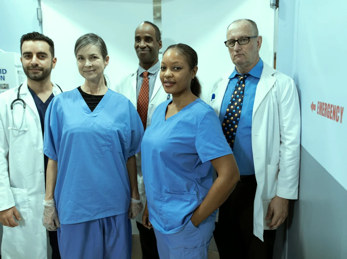 Equipe multidisciplinar de saúde caminhando junta em um corredor hospitalar